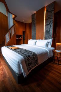 a bedroom with a large white bed with wooden walls at Hotel Le Temple Borobudur in Borobudur
