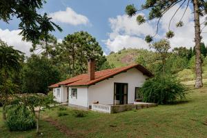 uma pequena casa branca no meio de um campo em Estalagem Tronador em Camanducaia