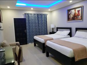 une chambre d'hôtel avec deux lits et une lumière bleue dans l'établissement Di Villa, à Port Antonio