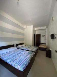 a bedroom with two beds and a tv on the wall at Dannykaela Transient House in Vigan