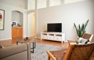 a living room with a tv and a couch and a table at Artisan's Retreat - Poolside Paradise Near Disney in Orlando