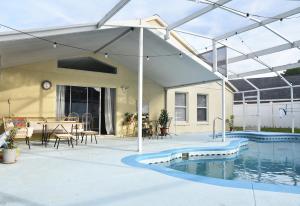a pavilion over a swimming pool with a table and chairs at Artisan's Retreat - Poolside Paradise Near Disney in Orlando