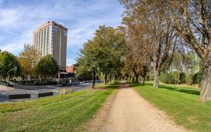 a dirt road in a park with trees and a tall building at Crowne Plaza Düsseldorf - Neuss, ein IHG Hotel in Neuss