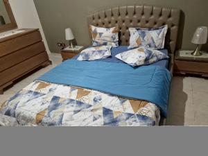 Bett mit blauer Bettdecke und Kissen in der Unterkunft Panorama III Cliniques les Jasmins in Ariana