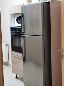 einen Kühlschrank aus Edelstahl in einer Küche mit einer Mikrowelle in der Unterkunft Panorama III Cliniques les Jasmins in Ariana