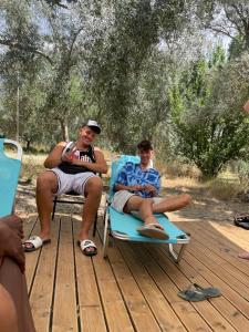 two men sitting in lawn chairs on a wooden deck at Mesa Vrysi in Vasiliki