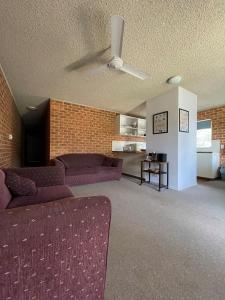 a living room with a couch and a ceiling fan at Ocean Breeze 4 - Bring your own linen. in South West Rocks