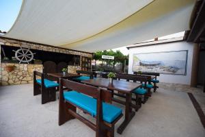un patio con mesas de madera y sillas azules en Rooms with a parking space Vir - 22996 en Vir