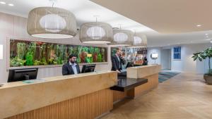 two men standing at a counter in a hotel lobby at Holiday Inn Auckland Airport by IHG in Auckland