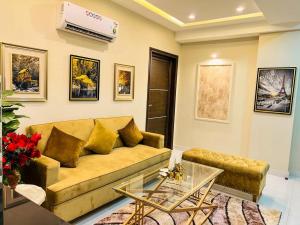 Bahria Town Lahore Prestige Apartments by LMY في لاهور: غرفة معيشة مع أريكة وطاولة زجاجية