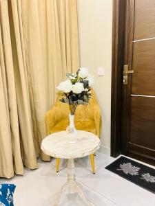 a table with a vase of flowers on top of it at Bahria Town Lahore Prestige Apartments by LMY in Lahore