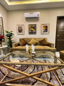 uma sala de estar com um sofá e uma mesa de vidro em Bahria Town Lahore Prestige Apartments by LMY em Lahore