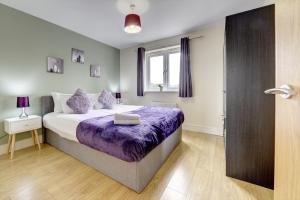 a bedroom with a bed with purple sheets and a window at Modern Comfort, 2BR, Ensuite, Parking in Rugby