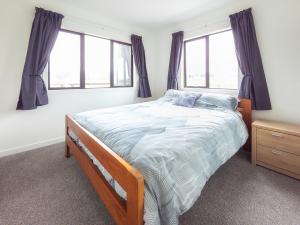 a bedroom with a bed and two windows at The Savvy Retreat - vineyard views in Martinborough 