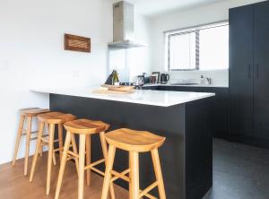 a kitchen with a counter with four stools at The Savvy Retreat - vineyard views in Martinborough 