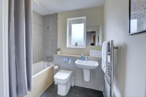 a bathroom with a toilet and a sink and a tub at Modern Comfort, 2BR, Ensuite, Parking in Rugby