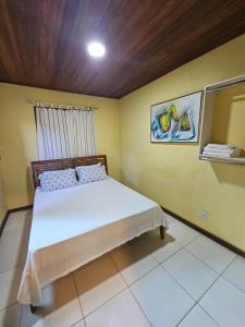 um quarto com uma cama branca numa parede amarela em Apartamento Buziano em Búzios