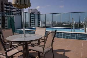 uma mesa e cadeiras numa varanda com piscina em Hosts BR - Studio Funcional em Boa Viagem(s/taxas) no Recife