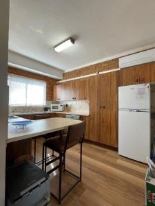a kitchen with a table and a white refrigerator at Woody Wonder Unit 2 South West Rocks in South West Rocks