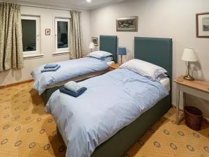 two twin beds in a room with two windows at The Byre in Tayvallich