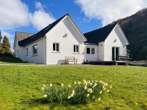 a white house in a field with flowers at The Byre in Tayvallich