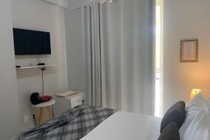 a white bedroom with a bed and a television at Hosts BR - La Serena Suíte Cumbuco in Cumbuco