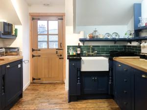 cocina con armarios azules y fregadero blanco en Hen Joppa, en Newlyn