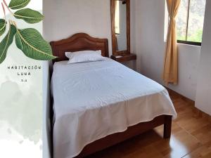 1 dormitorio con 1 cama con colcha blanca en Killari-Hospedaje Puro Jita, en Lunahuaná