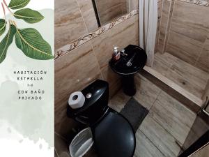 a bathroom with a black toilet and a sink at Killari-Hospedaje Puro Jita in Lunahuaná