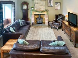 Old Kielder Castle Cottage في كييلدر: غرفة معيشة مع أريكة جلدية ومدفأة