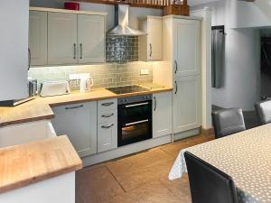 a kitchen with white cabinets and an oven at Old Kielder Castle Cottage in Kielder