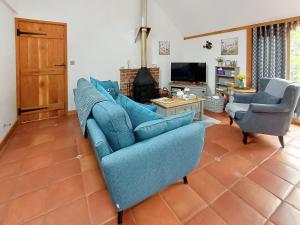 a living room with a blue couch and two chairs at Meadow Barn in Wool