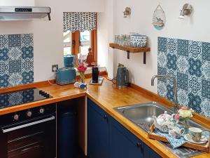 una cocina con armarios azules y fregadero en Meadow Barn en Wool