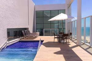 a house with a swimming pool and a table with an umbrella at Hosts BR - Flats Frente Mar c/ Cozinha in Recife