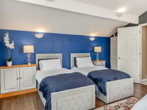 two beds in a bedroom with blue walls at Dunburgh Wood in Beccles