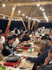 grupa ludzi siedzących przy długich stołach jedzących jedzenie w obiekcie The Blooms Villas w mieście Bedugul