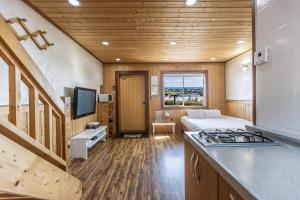 a bedroom with a bed and a kitchen with a stove at Habada Pension in Seogwipo