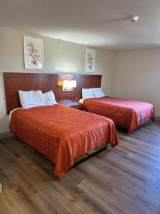 Cette chambre d'hôtel comprend 2 lits avec des draps rouges. dans l'établissement Rosewood Inn, à Union City