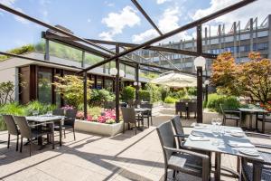 un patio extérieur avec des tables et des chaises et un bâtiment dans l'établissement Crowne Plaza Zürich, an IHG Hotel, à Zurich