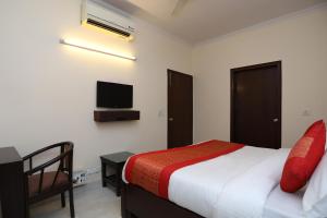 een slaapkamer met een bed en een tv aan de muur bij OYO Krishna residency in Gurgaon
