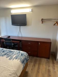 Zimmer mit einem Schreibtisch, einem TV und einem Bett in der Unterkunft Rosewood Inn in Union City