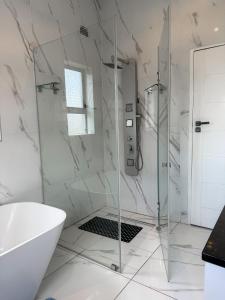 La salle de bains blanche est pourvue d'une douche et d'une baignoire. dans l'établissement holiday villa, à Harare