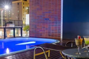 una piscina en la azotea de un edificio con mesas y sillas en Hosts BR - Flat Vista Mar no Meireles, en Fortaleza