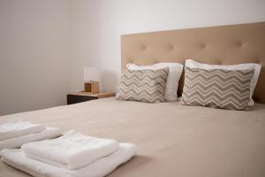 a bed with two white towels on it with two pillows at Casa do Sal in Sesimbra