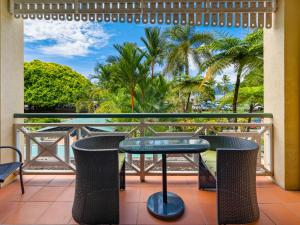 a balcony with a table and chairs and palm trees at Waterfront Terraces in Cairns