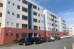 a parking lot with cars parked in front of a building at Hosts BR - Apartamentos funcionais in Fortaleza