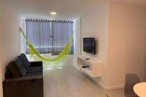 a living room with a couch and a green hammock at Hosts BR - Apartamentos funcionais in Fortaleza