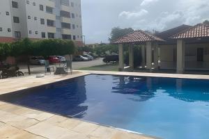a large blue swimming pool in front of a building at Hosts BR - Apartamentos funcionais in Fortaleza