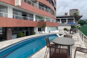 einen Balkon mit einem Tisch und Stühlen neben einem Pool in der Unterkunft Hosts BR - Cobertura duplex frente mar in Fortaleza