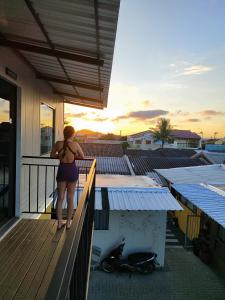 a woman standing on a balcony watching the sunset at Maga hospedagem in Penha